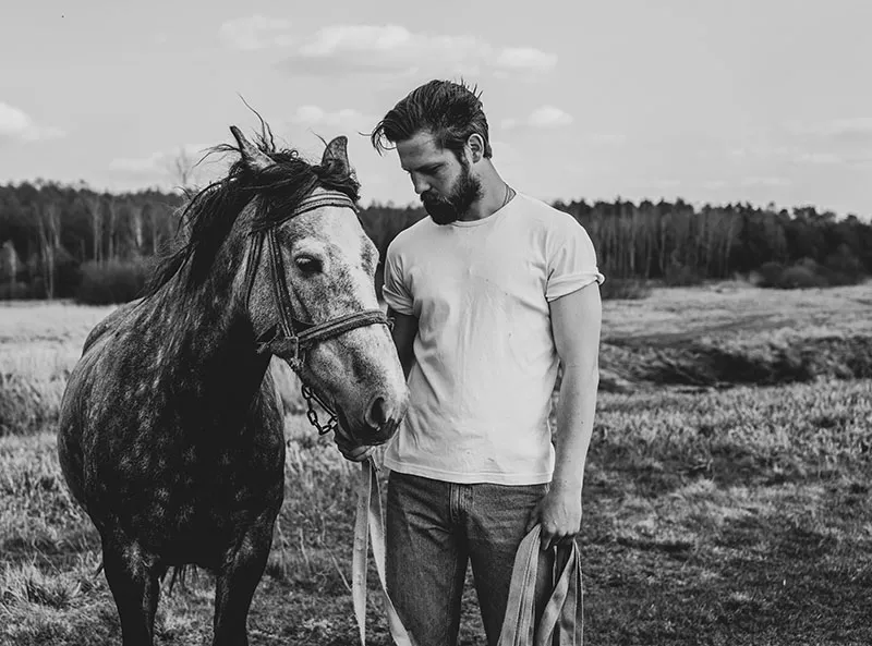 man with a horse standing in a field