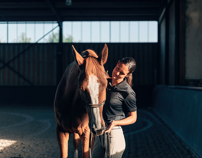 woman petting a horse in front of a barn